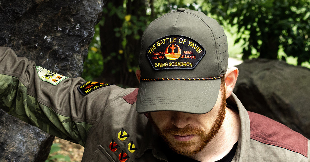 Person wearing a cap with 'The Battle of Yavin' design and a matching jacket outdoors.