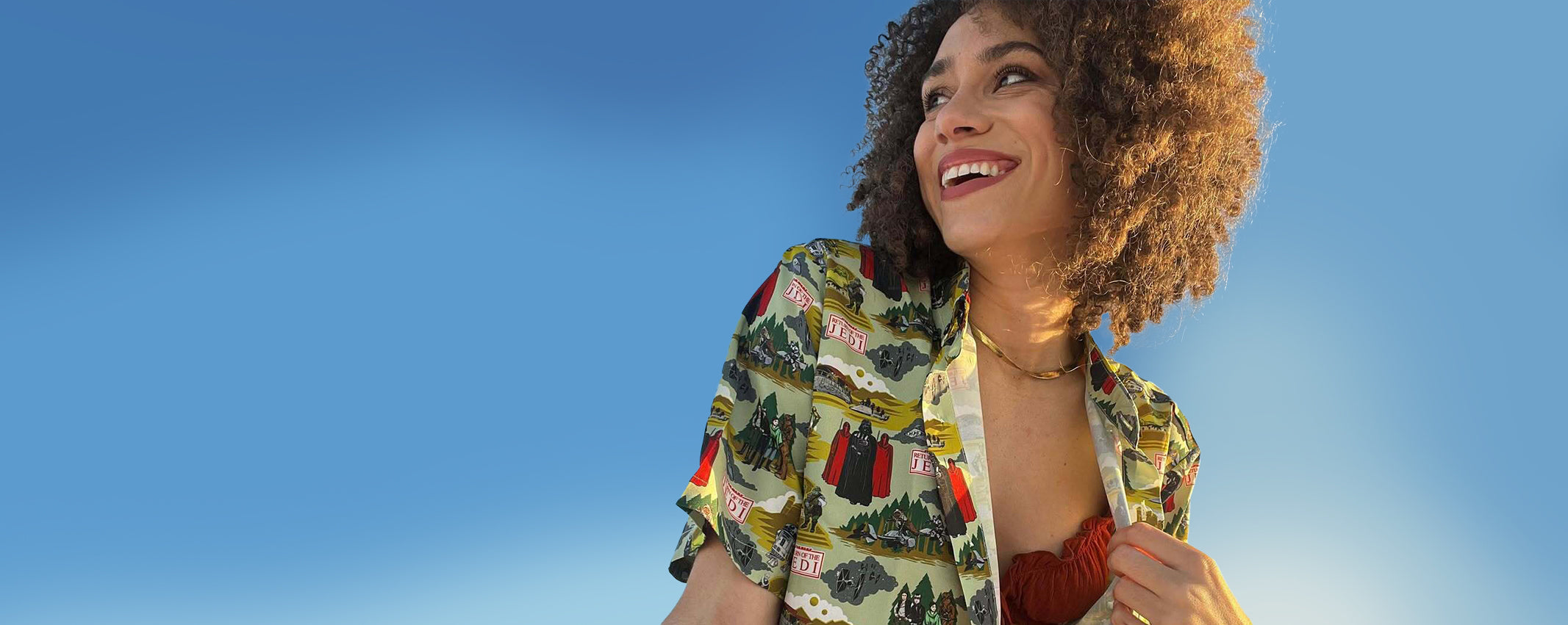 Woman wearing a colorful button down against a clear blue sky