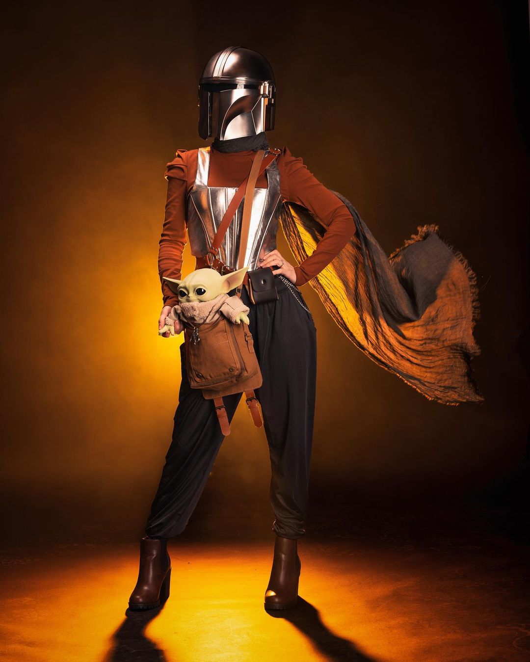 woman in mandalorian outfit with official bag and grogu toy
