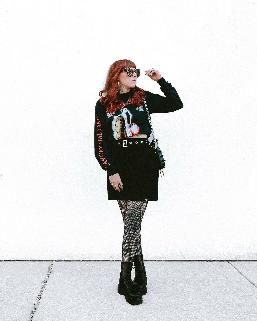 Person wearing a graphic sweater and black skirt with patterned tights on a white background