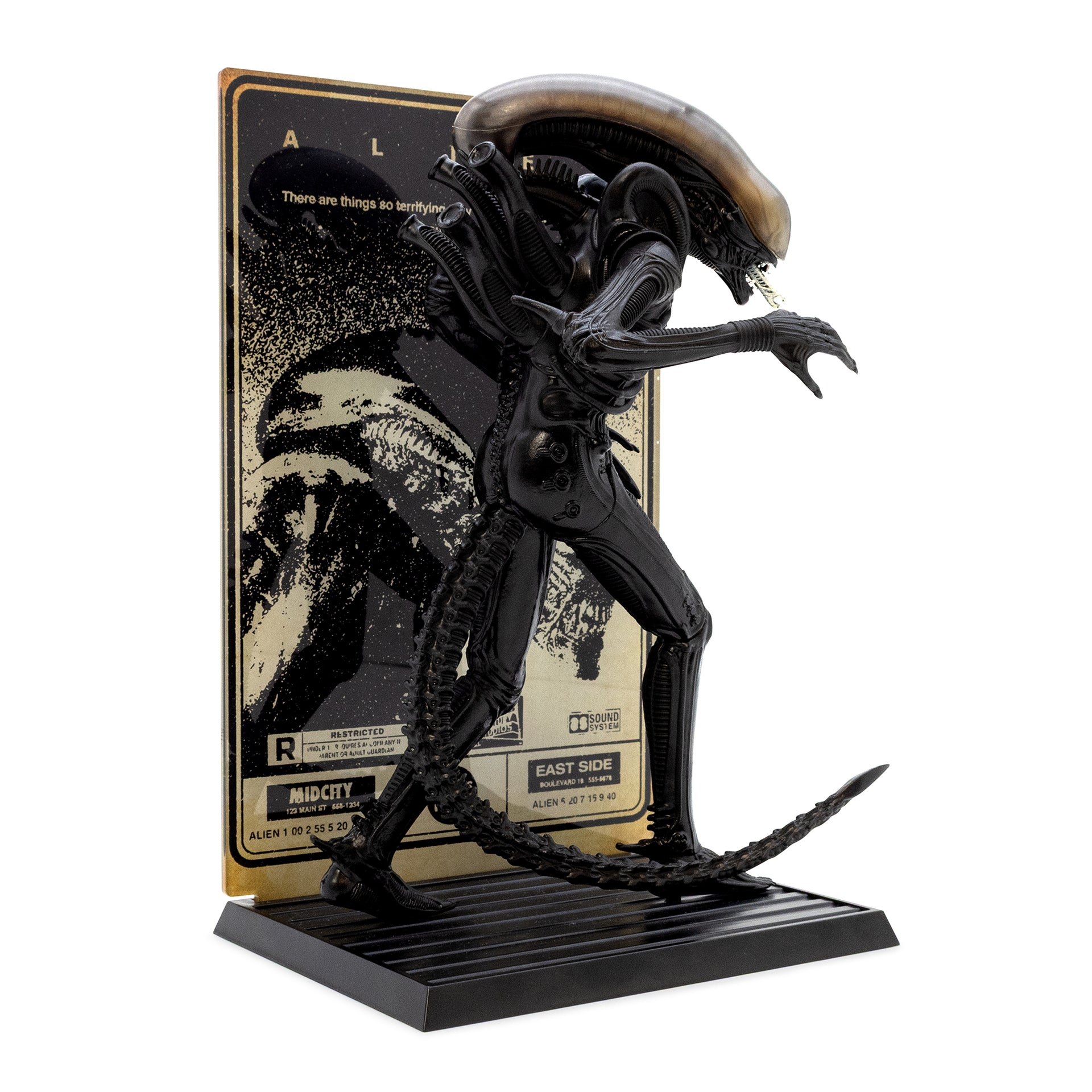 Black alien figure on a stand with a movie poster in the background
