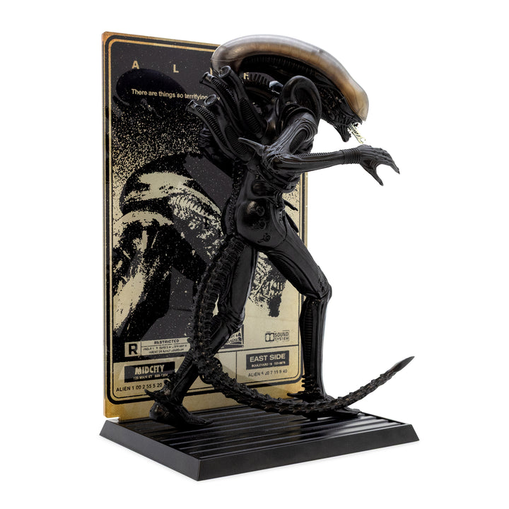 Black alien figure on a stand with a movie poster in the background