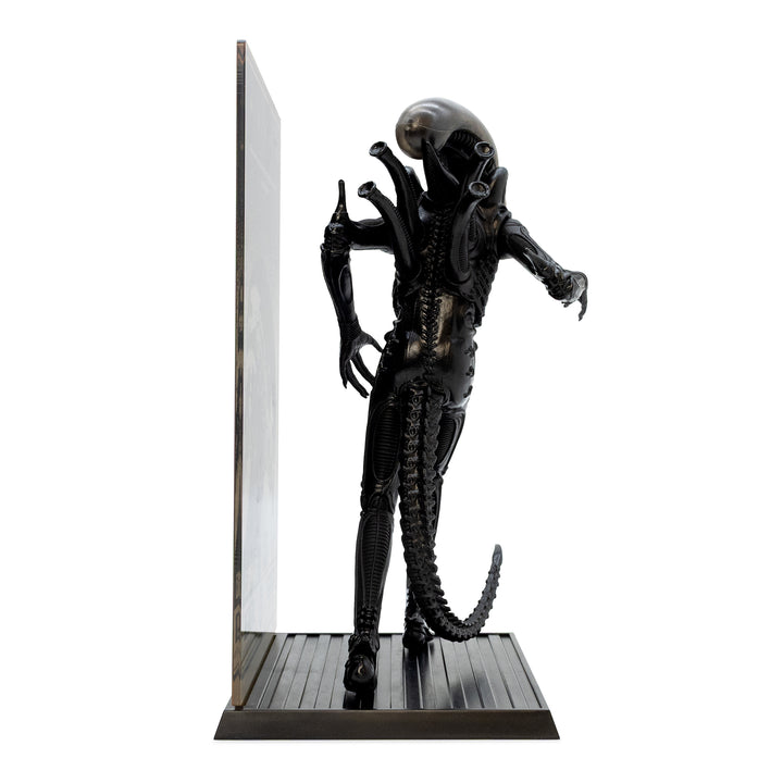 Alien figurine on a stand with a white background