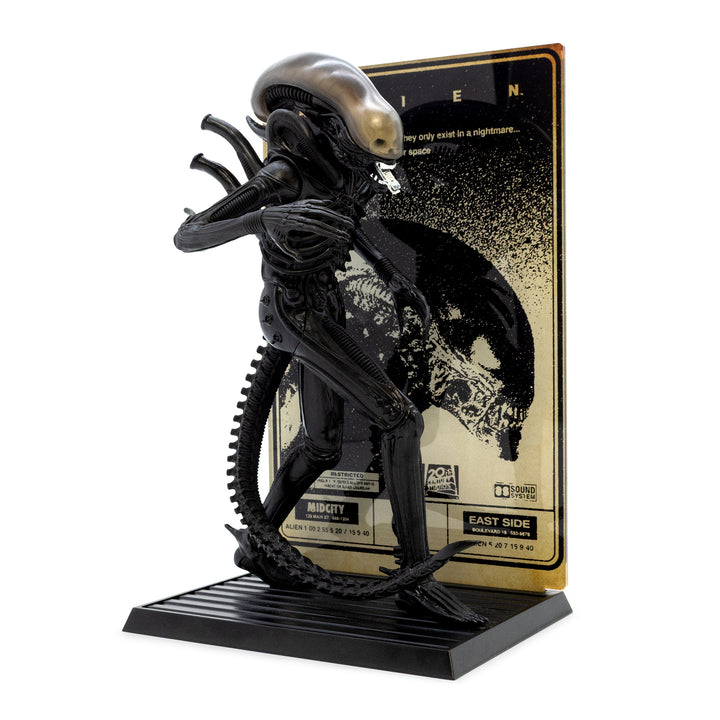 Black alien figure on a stand with a gold and black background