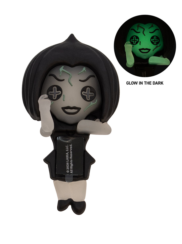A stylized chibi figure with black hair, pale gray face and hands, and a black outfit, shown on a white background with a circular inset demonstrating a green glow-in-the-dark effect.