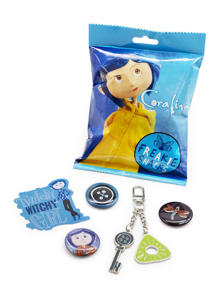 A Coraline-themed accessory set displayed on a white background, featuring a blue character sticker, a button, a keychain with a key and heart-shaped charm, a round pin, and a butterfly charm, alongside its blue packaging bag.