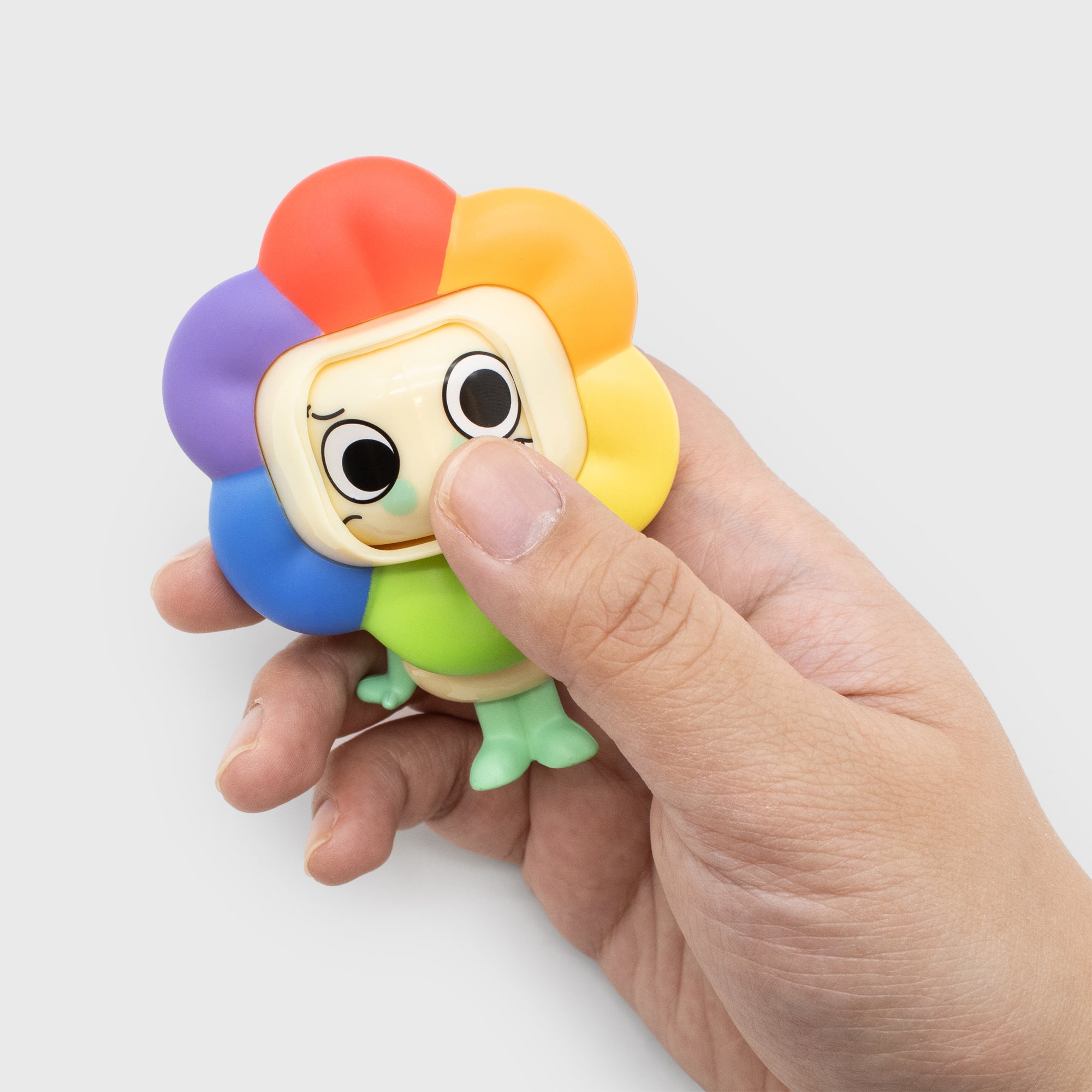 Colorful character toy held by a hand on a white background