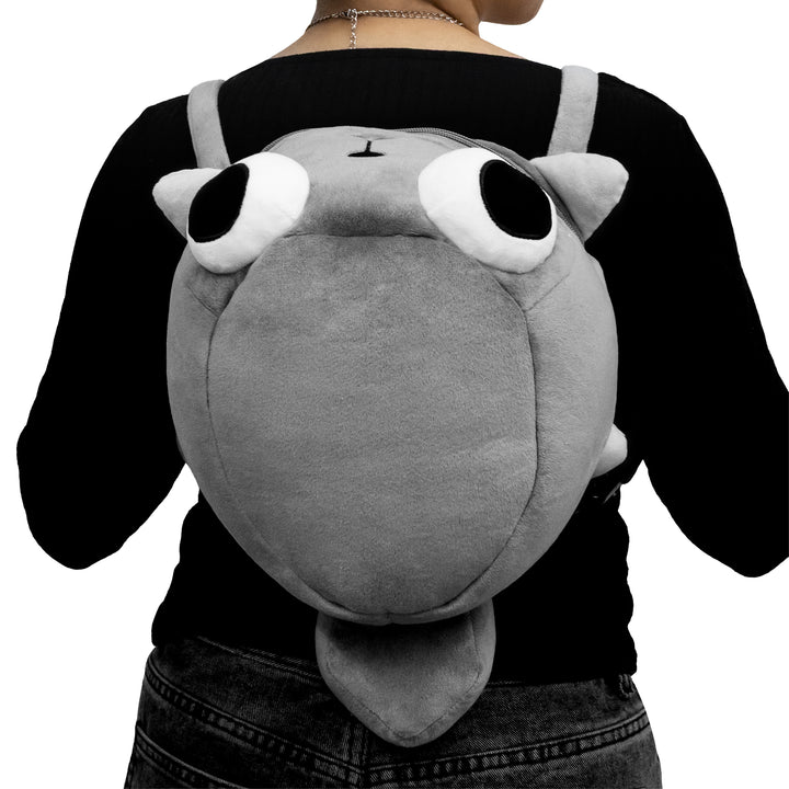 Person wearing a plush backpack shaped like a cartoonish creature with large eyes.