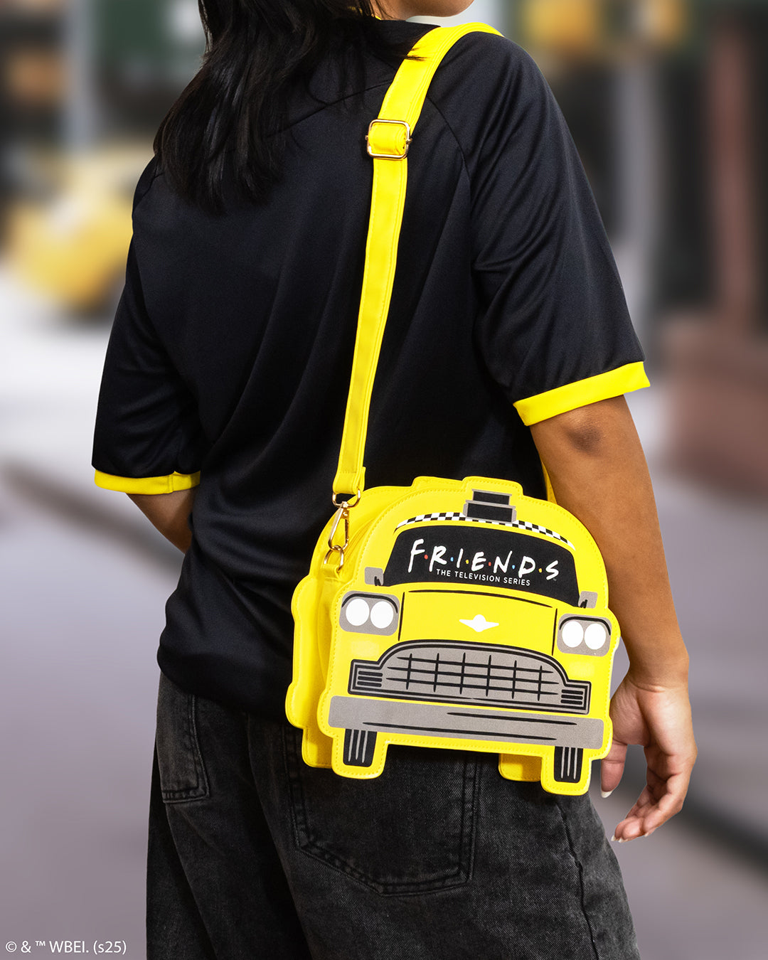 Person holding a yellow taxi-shaped bag with 'Friends' logo.