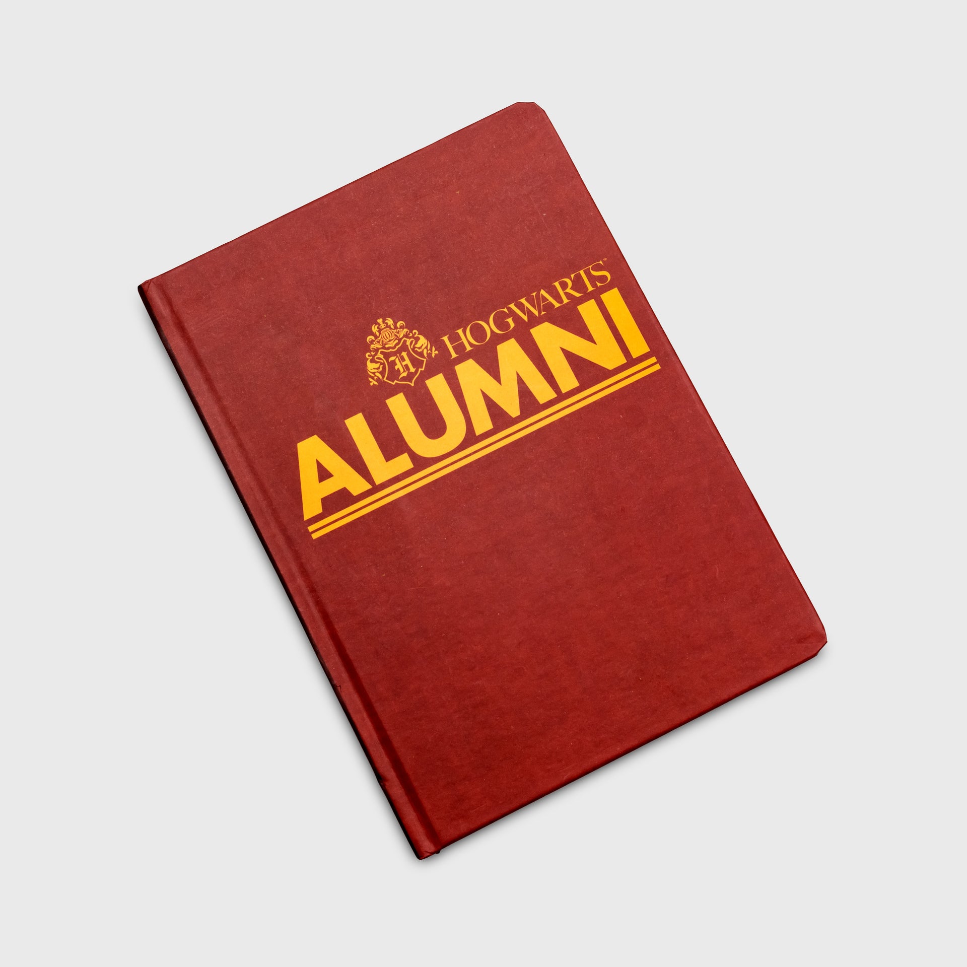 notebook. image on cover: hogwarts symbol. text: hogwarts alumni