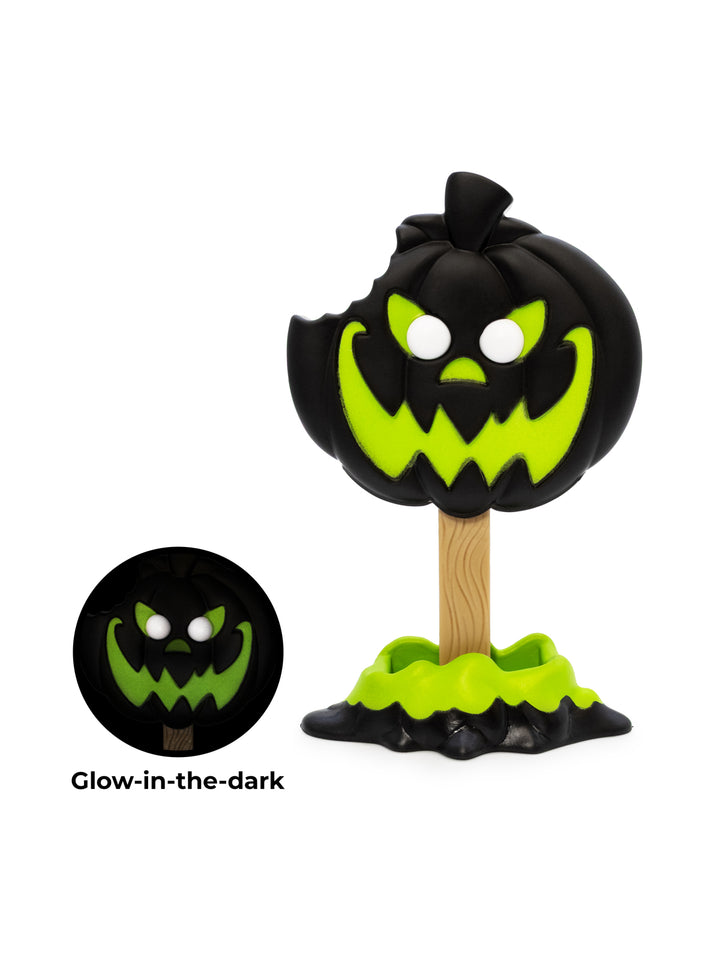 A jack-o'-lantern Halloween figure on a wooden stand, shown on a white background with a circular inset demonstrating its glow-in-the-dark effect. The pumpkin is black with a bright neon green glowing face and a small black mist at the base.