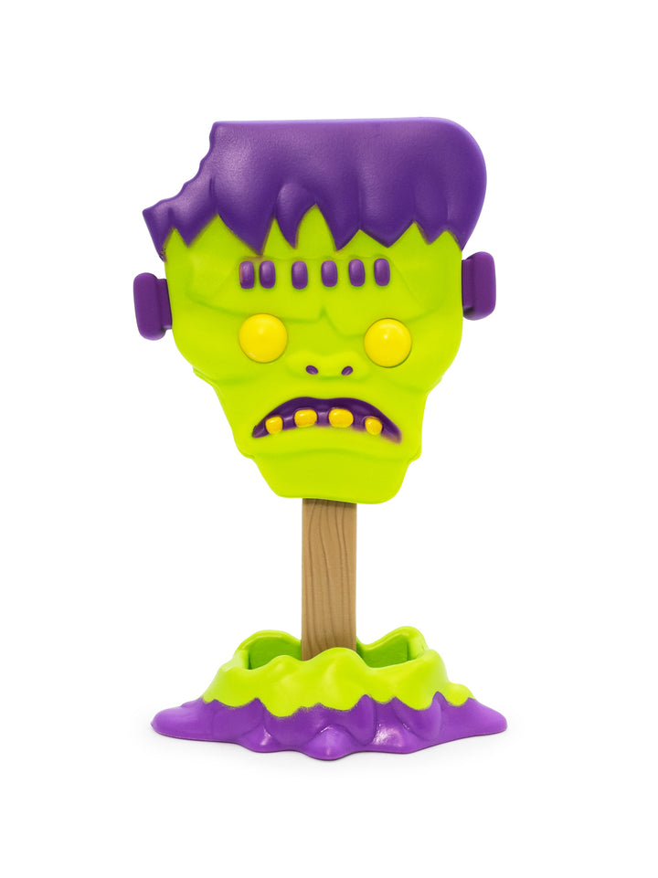 A plastic Frankenstein's monster head stand on a wooden stick with a purple base, isolated on a white background.