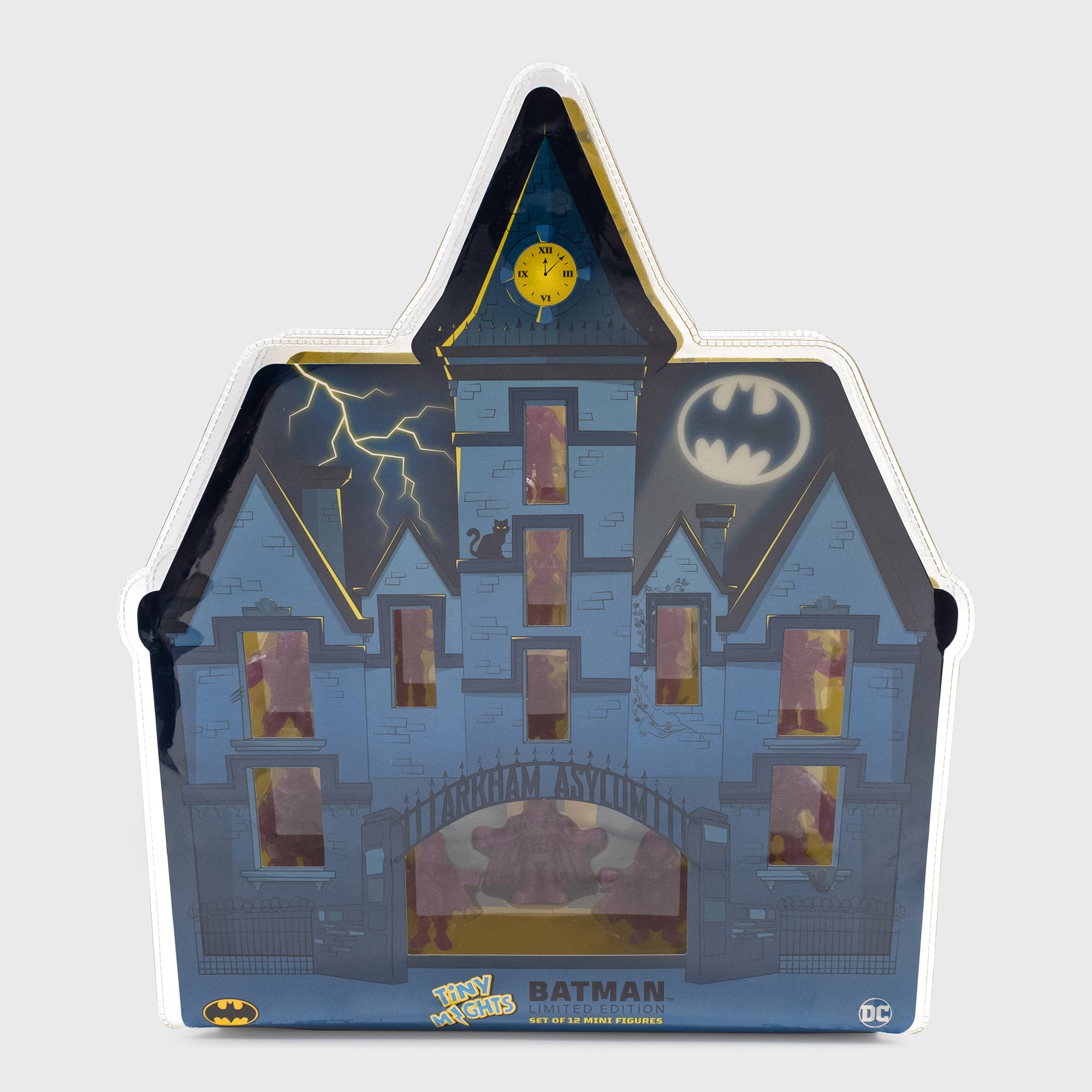batman tiny mights arkham asylum 12 pack packaging. image of packaging: arkham asylum building with figures in each window. lightning and batman signal in sky. text: tiny mights batman limited edition set of 12 mini figures.