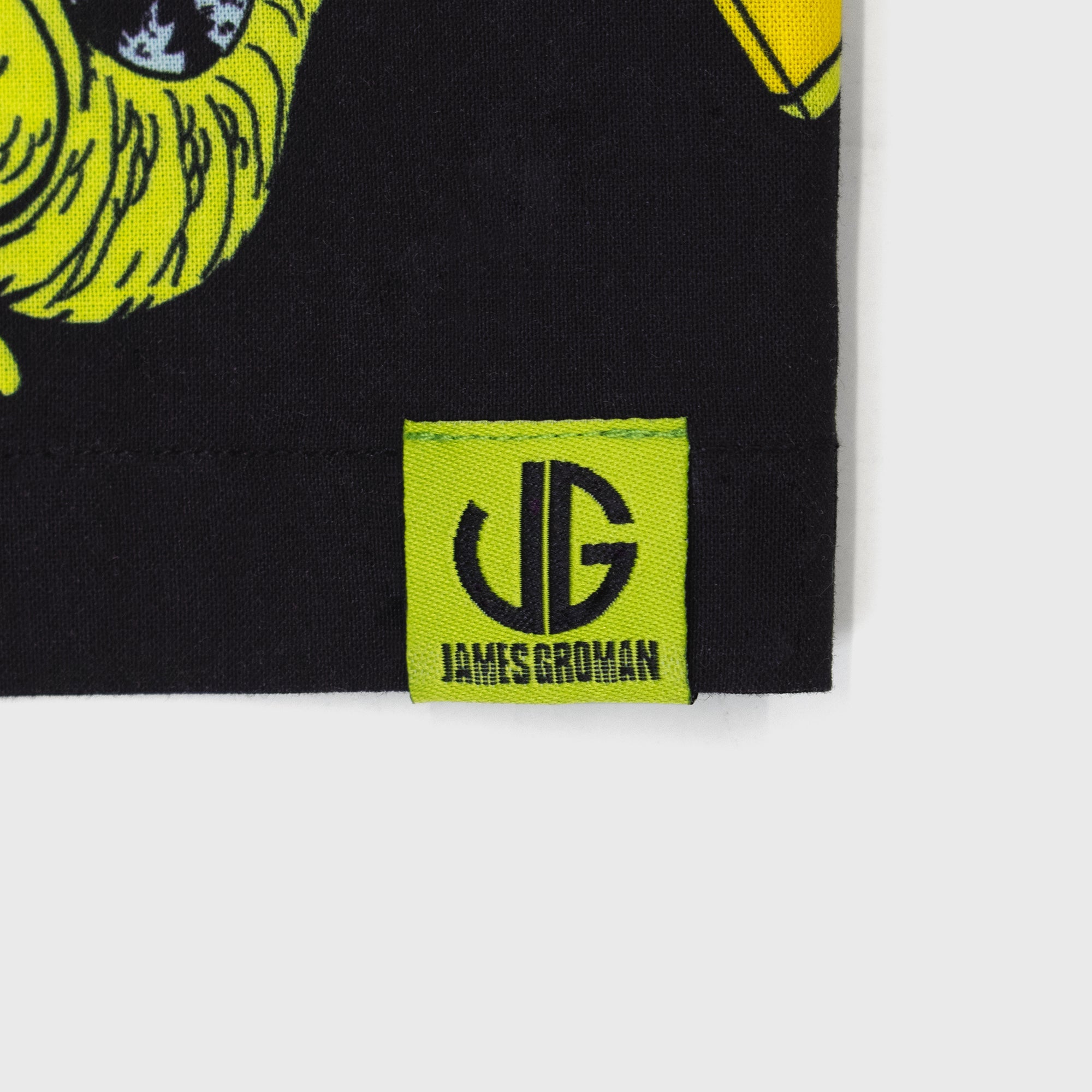 james groman reptar woven shirt. close up of tag on bottom. image: james groman logo. text: james groman