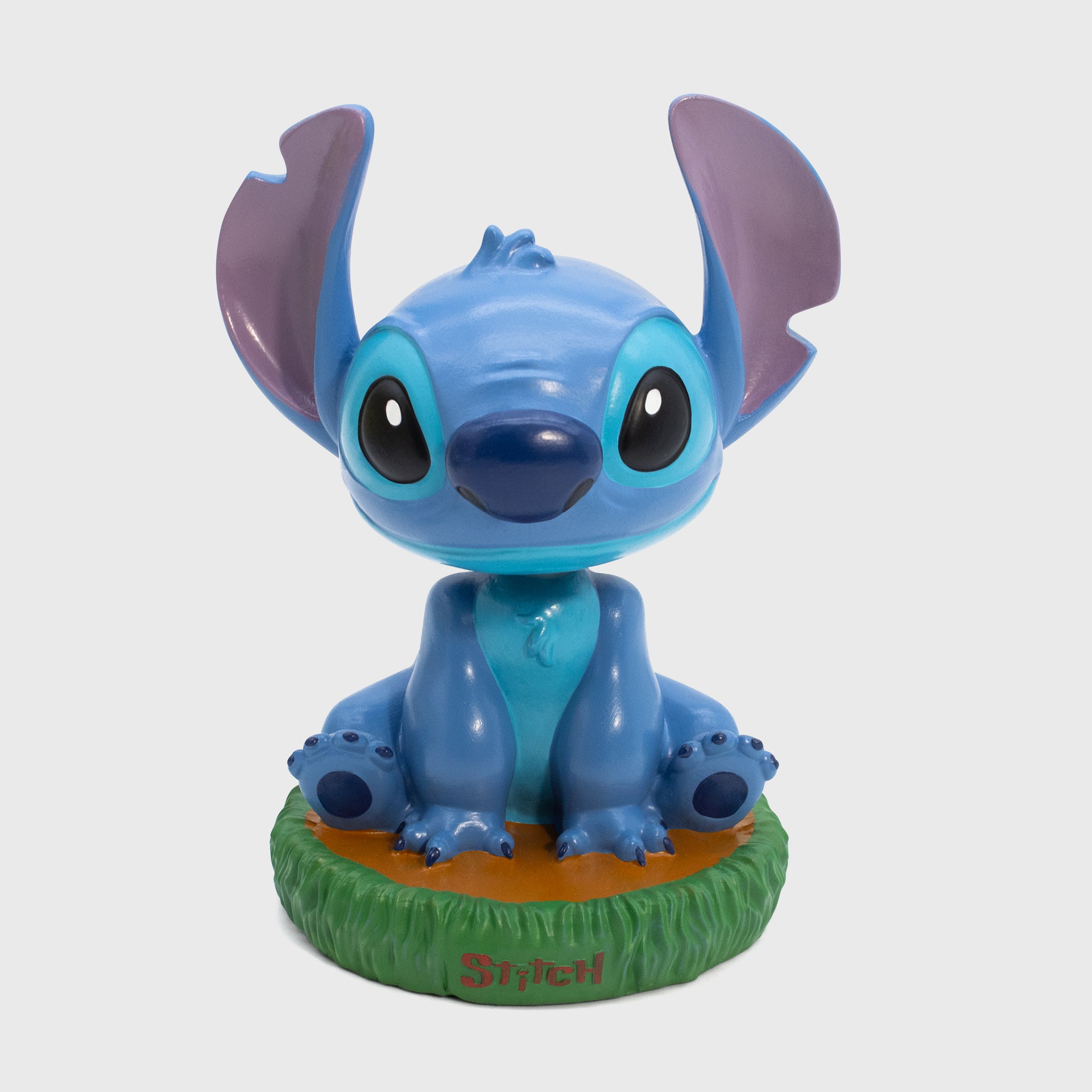 stitch bobblehead. stitch sitting on grass. text on bottom of stand: stitch
