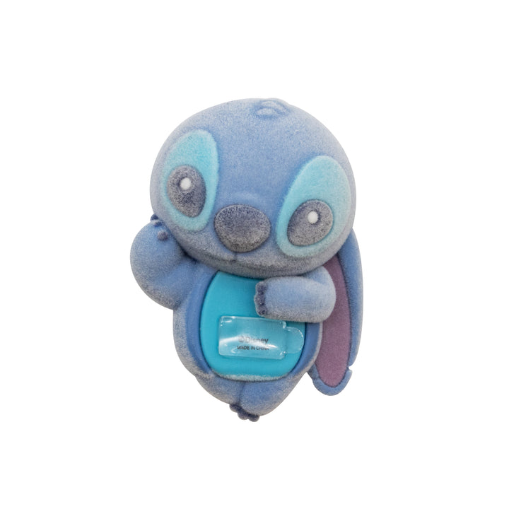 A blue plush toy character with large eyes, a gray snout, and a small clear plastic attached to its chest, shown against a plain white background.
