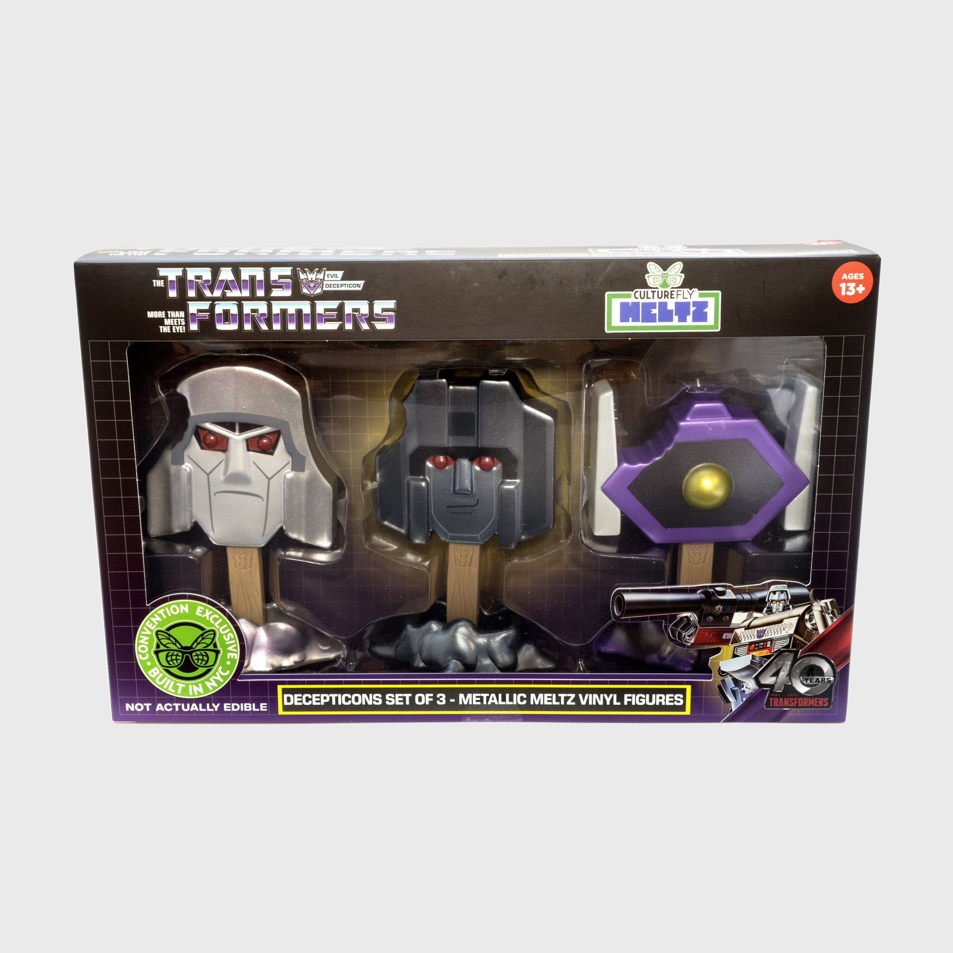front of 3-pack packaging. showing all 3 meltz. text: the transformers evil decepticon more than meets the eye! culturefly meltz. ages 13+. not actually edible. convention exclusive built in nyc. decepticons set of 3 - metallic meltz vinyl figures. 40 years transformers.