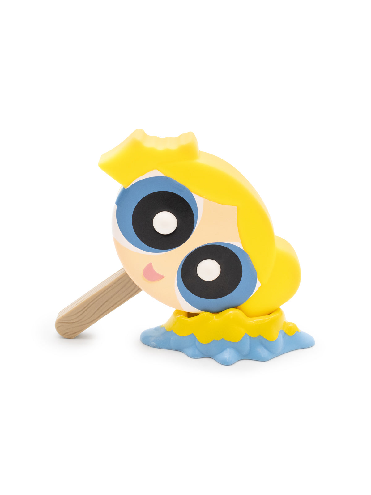 Toy figure of a character with large eyes and yellow hair with a popsicle stick on a white background
