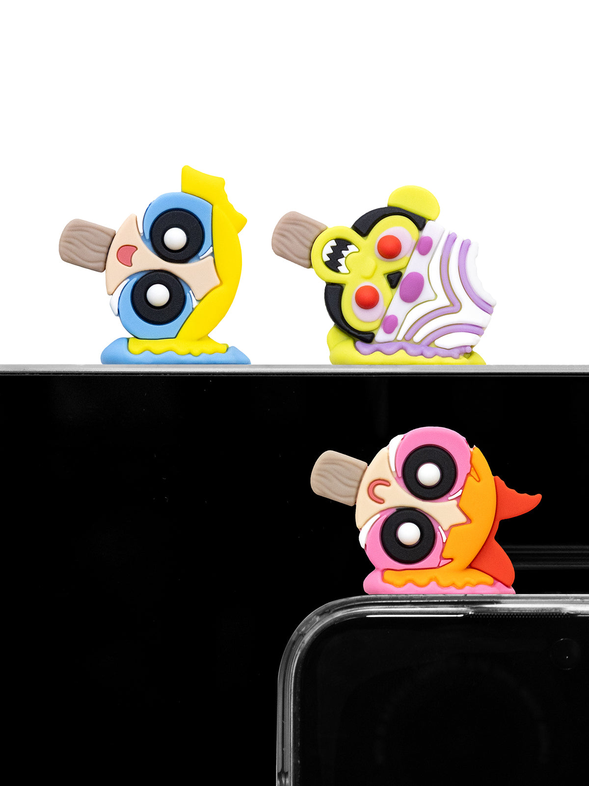 Three colorful cartoon-style phone case bumpers with large eyes and expressive faces, shown on a white background with one example mounted on a phone case against a black background.