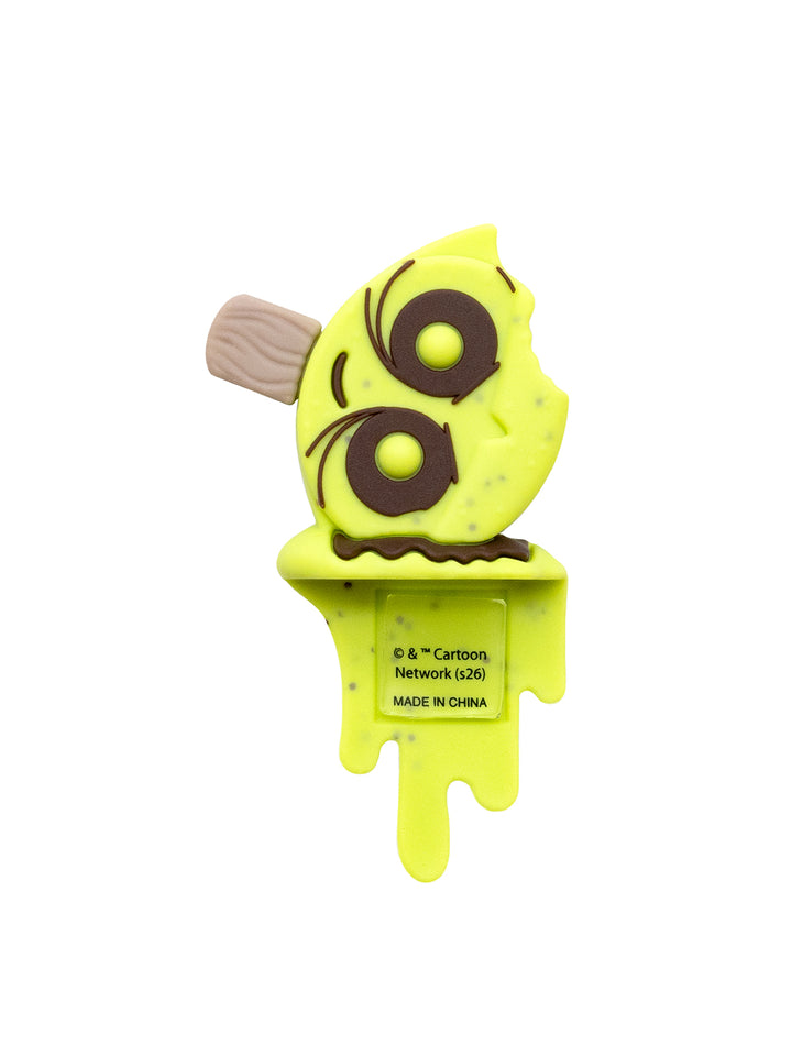 A novelty ice pop shaped figure like a cartoon face with a brown stick, featuring a bright yellow-green body with dark brown eyes and a small beige mouthpiece, on a plain white background.