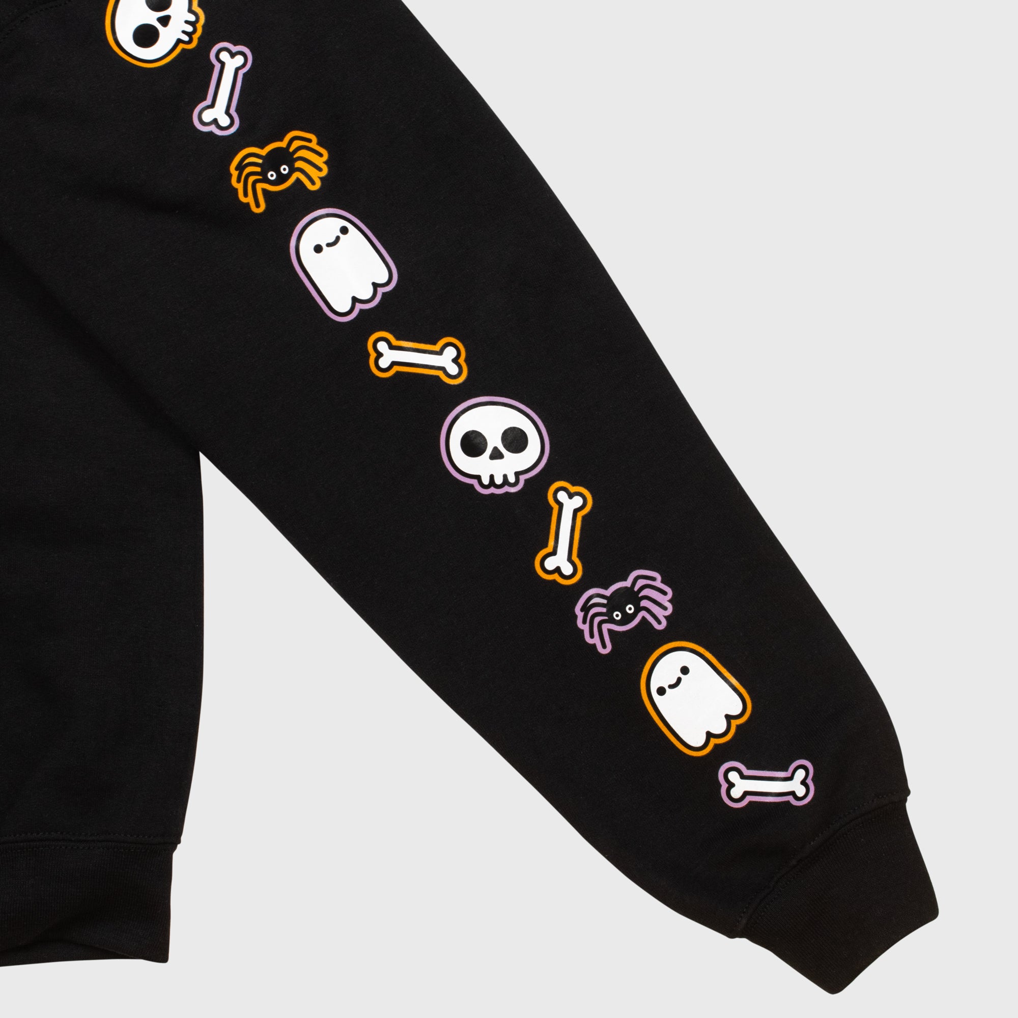close up of left sleeve. image: repeating pattern of skull, bone, spider, ghost.
