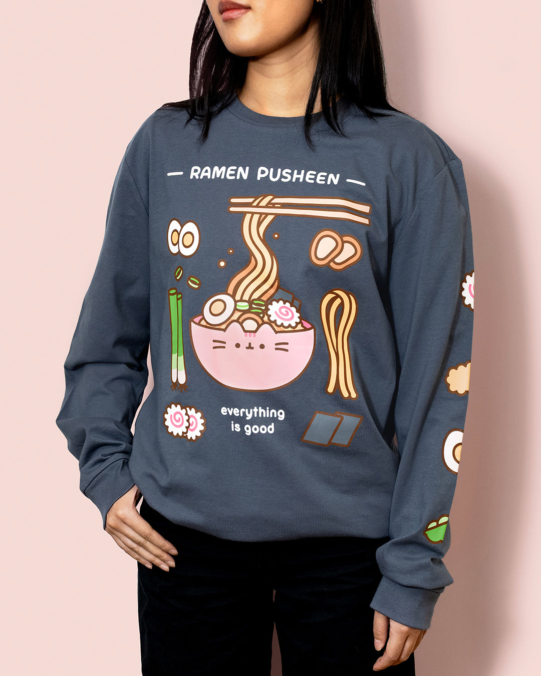 Person wearing a blue sweatshirt with 'Ramen Pusheen' graphic design on a pink background