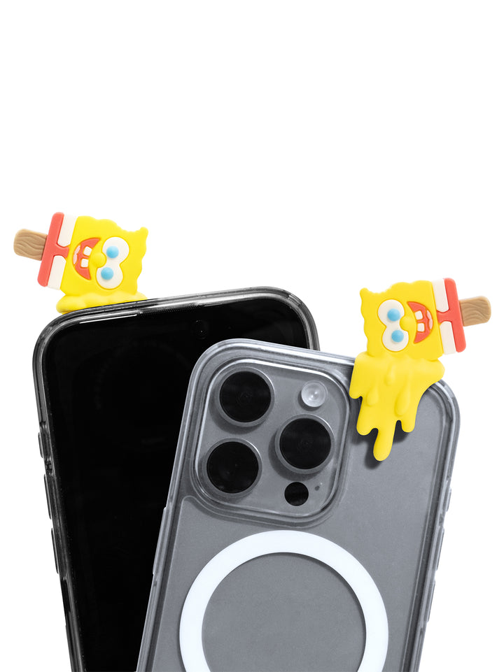 A clear MagSafe-compatible phone case on a gray iPhone, shown with two yellow SpongeBob-themed popsicle clips attached near the top corners, against a plain white background.