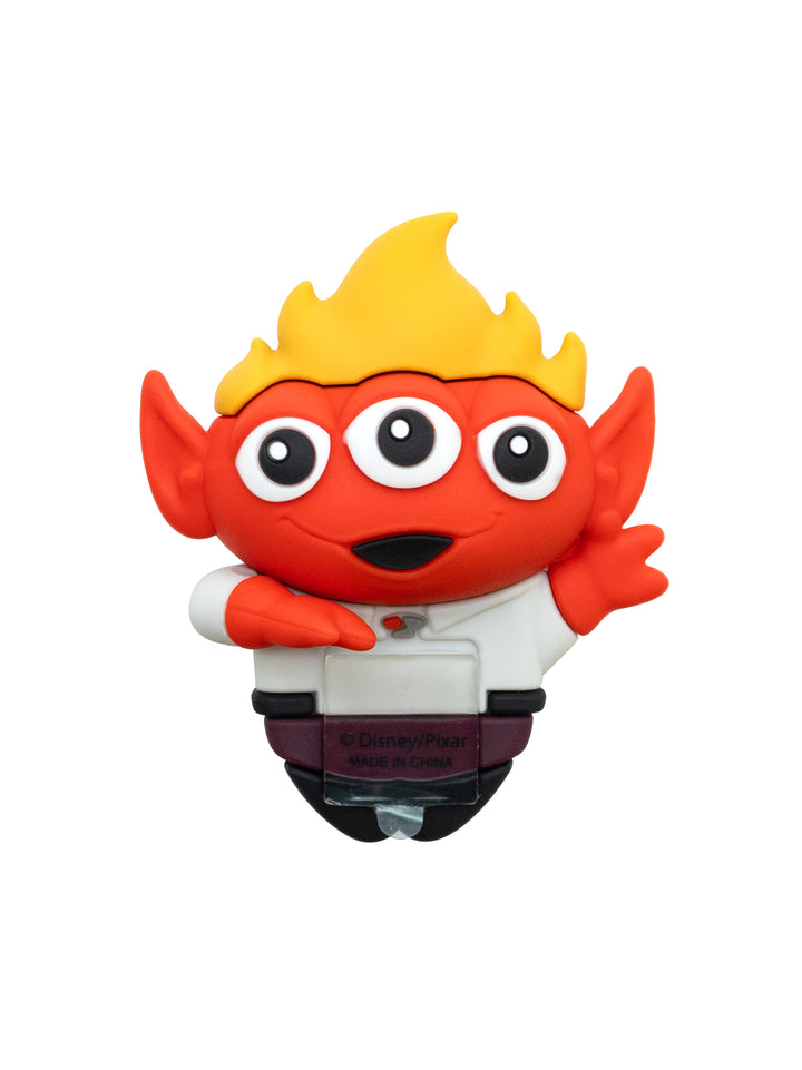 A small cartoon character figurine featuring a red face and arms, yellow flame-like hair, large white eyes, and a white shirt with a dark waistband, shown on a plain white background.