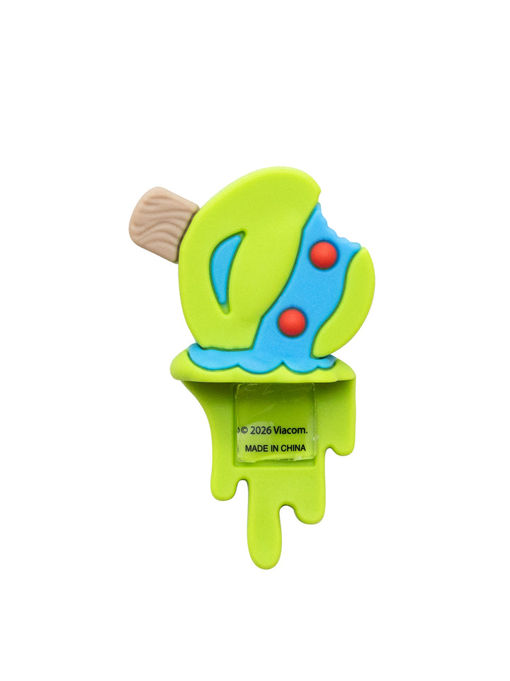 A novelty figure shaped like a melting popsicle, featuring a bright lime green body, a blue mask with two red dots, and a brown wooden stick, shown on a plain white background.
