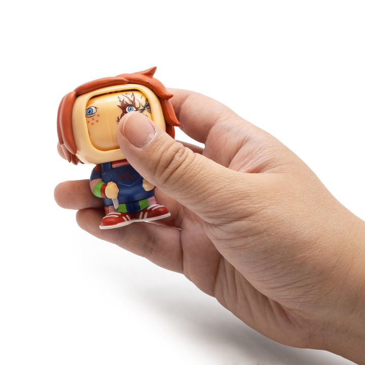 Hand holding a small figurine with a colorful design on a white background