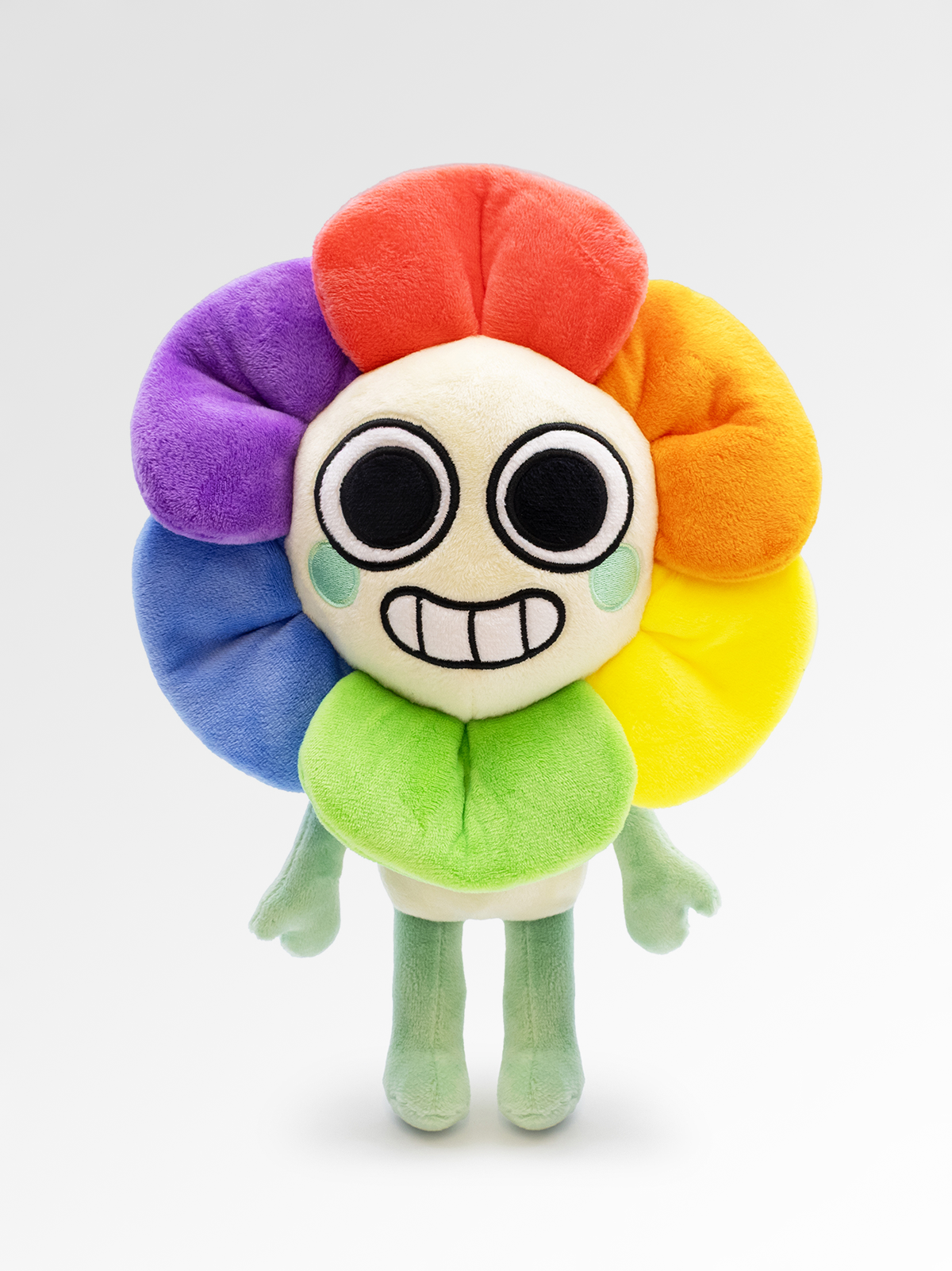 Colorful plush toy with a round face and flower-like design on a white background