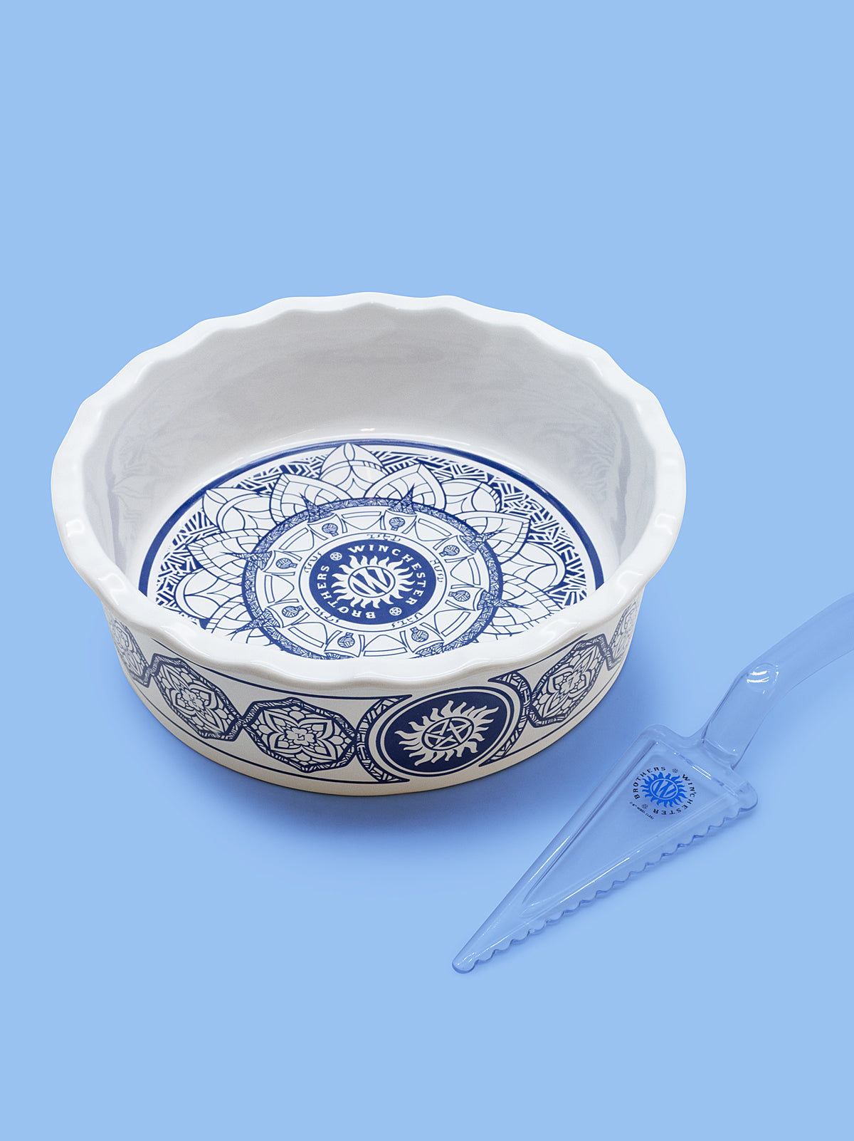 Decorative ceramic bowl with blue patterns and a small tool on a light blue background