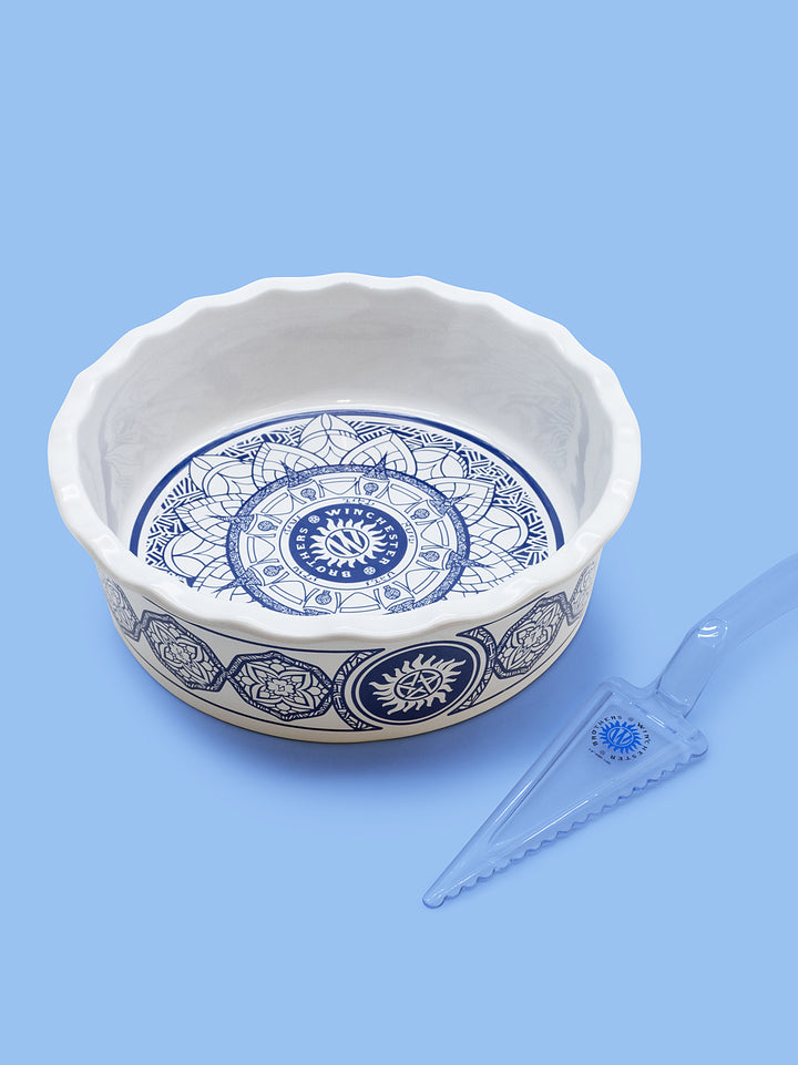 Decorative ceramic bowl with blue patterns and a small tool on a light blue background