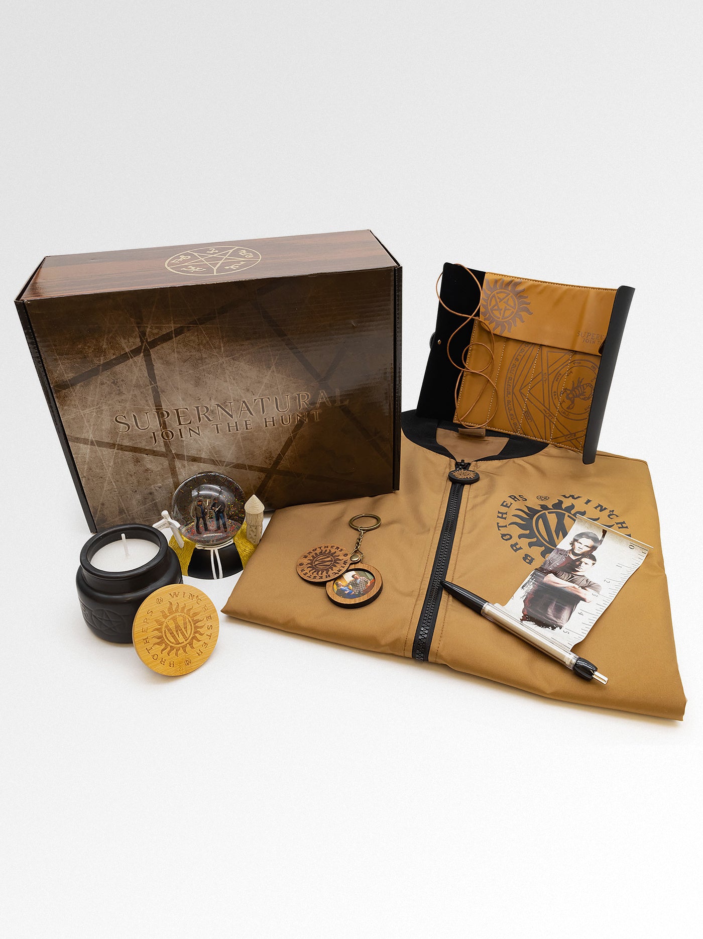 Collection of leather-bound items including a journal, keychain, and small container on a white background.
