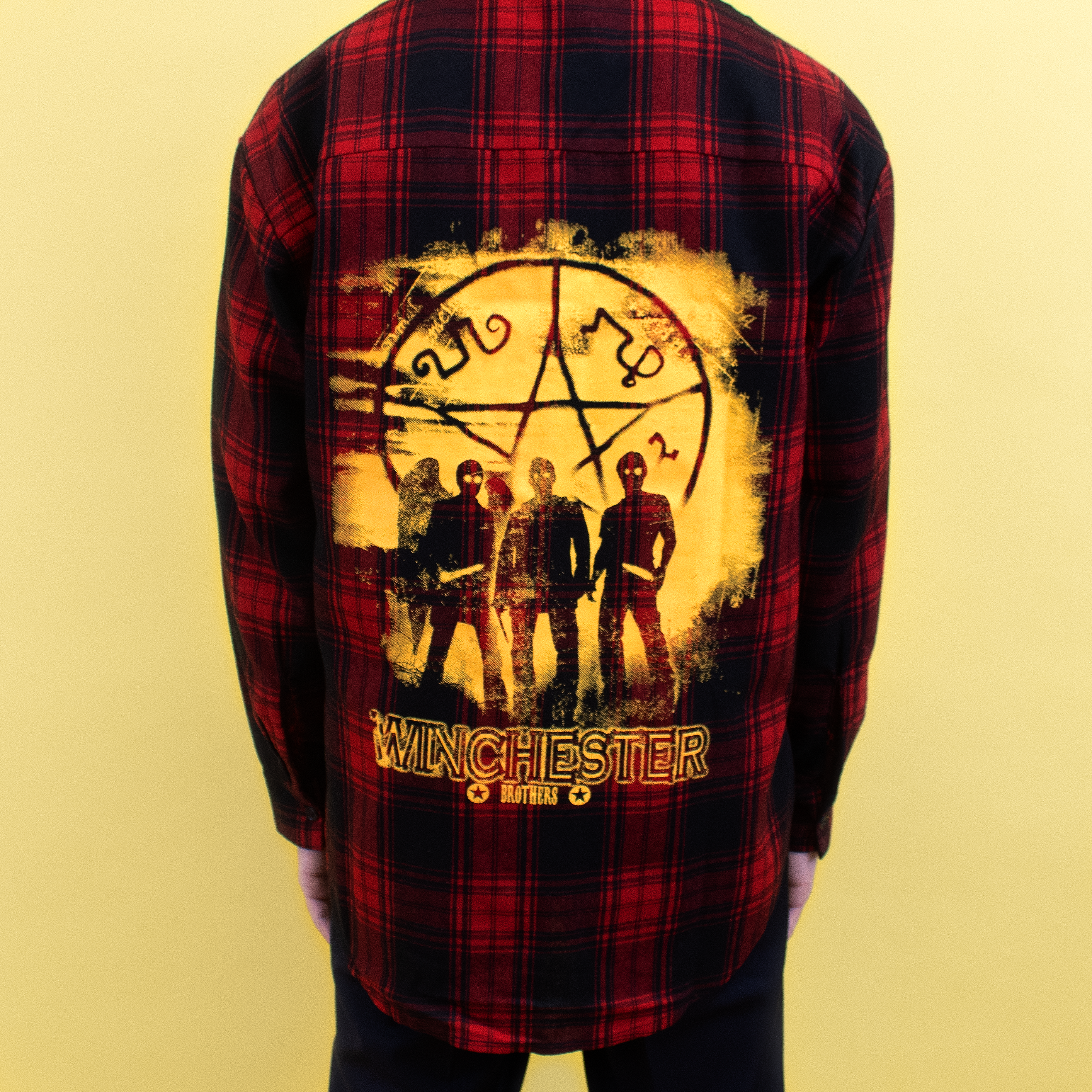 supernatural spookynatural plaid shirt back. image: castiel, dean, and sam in front of symbol. text: winchester brothers.