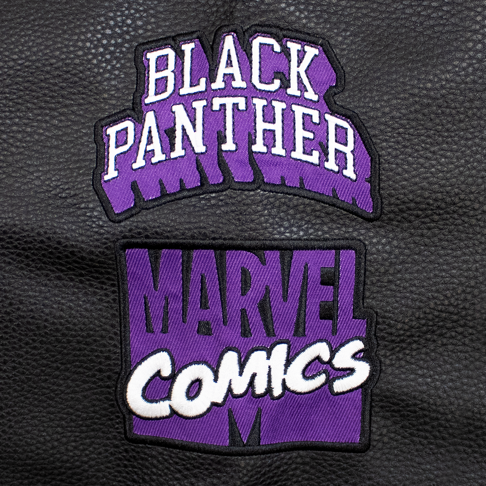 close up of sleeve patch. 2 patches. purple and white black panther written out. purple and white marvel comics.